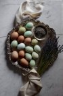 Барвисті яйця на старовинному металевому лотку з лавандовими гілочками на білому мармурі — стокове фото