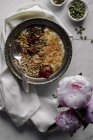 Bowl of yogurt with oats and seeds on table with peonies — Stock Photo