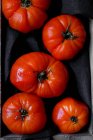 Fresh ripe red tomatoes on black fabric — Stock Photo