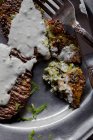 Крупным планом оладьи из брокколи с соусом тахини на серебряной тарелке с столовыми приборами — стоковое фото
