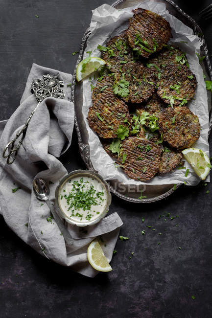 Broccoli cheese fritters and tahini sauce on platter with fabric — Stock Photo