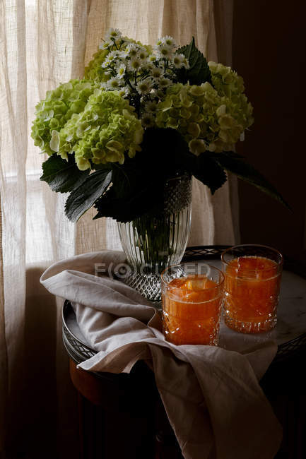 Cantaloupe juice in glasses and bouquet of fresh cut flowers — Stock Photo