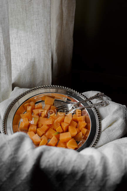 Fresh diced cantaloupe on metal platter with fabric — Stock Photo