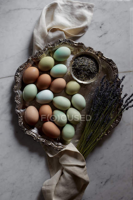 Ovos coloridos na bandeja de metal vintage com raminhos de lavanda em mármore branco — Fotografia de Stock
