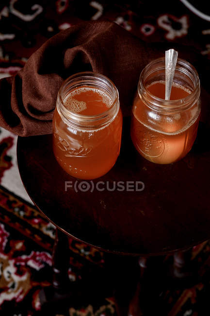 Jars of organic ghee on wooden chair with fabric — Stock Photo
