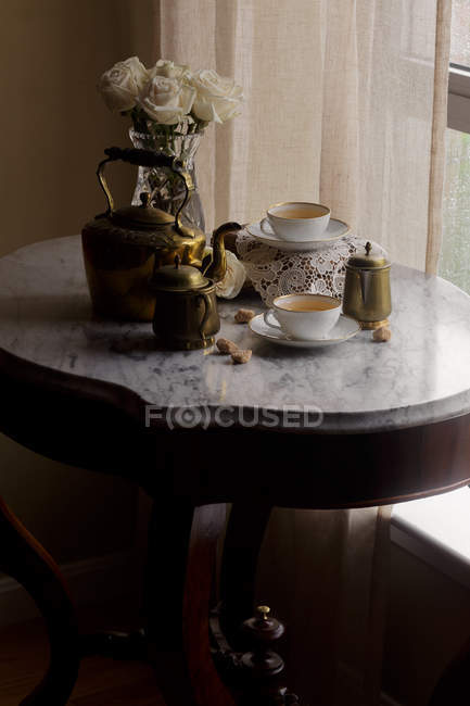 Tea in cups and vintage teapot on white marble tabletop — Stock Photo