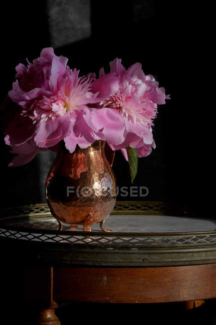 Fresh cut pink peonies in vintage copper vase — Stock Photo