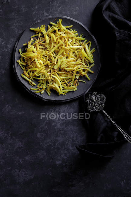 Patatine fritte su piatto su superficie nera — Foto stock