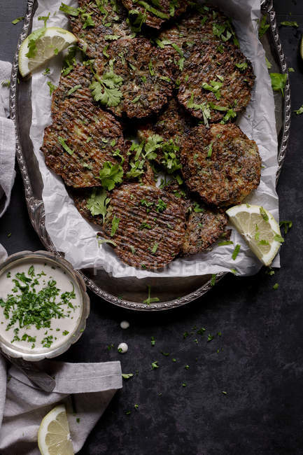 Broccoli cheese fritters and tahini sauce on platter on dark background — Stock Photo