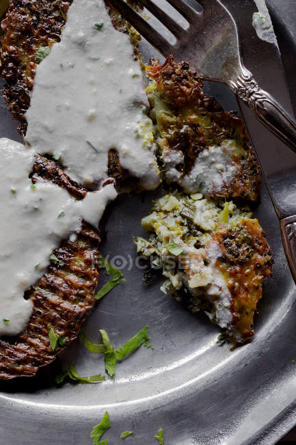 Gros plan des beignets au fromage brocoli avec sauce tahini sur une assiette argentée avec couverts — Photo de stock