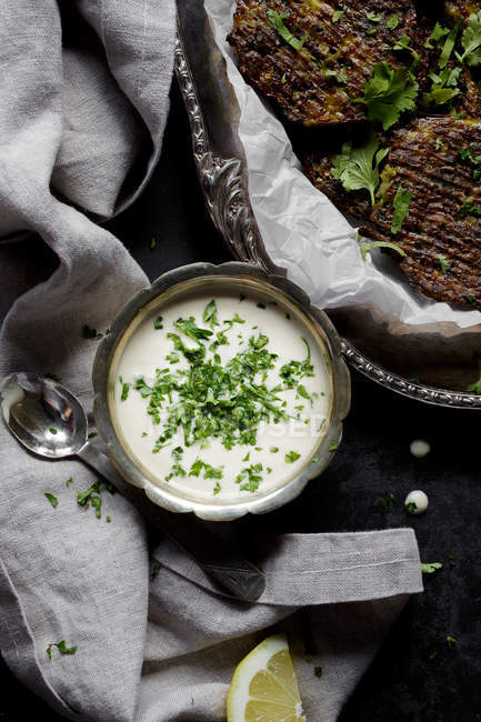 Соус тахини в миске и сырные оладьи брокколи — стоковое фото