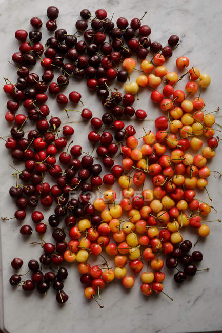 Fresh red and yellow cherries on white marble surface — Stock Photo