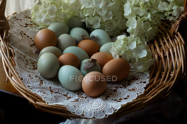 Bunte Eier im Korb mit frischen Schnittblumen — Stockfoto