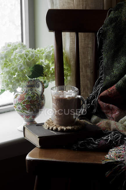 Горячий шоколад с зефиром в стеклянной чашке на деревянном стуле — стоковое фото