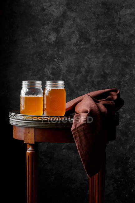 Jars of organic ghee on small wooden table with fabric — Stock Photo