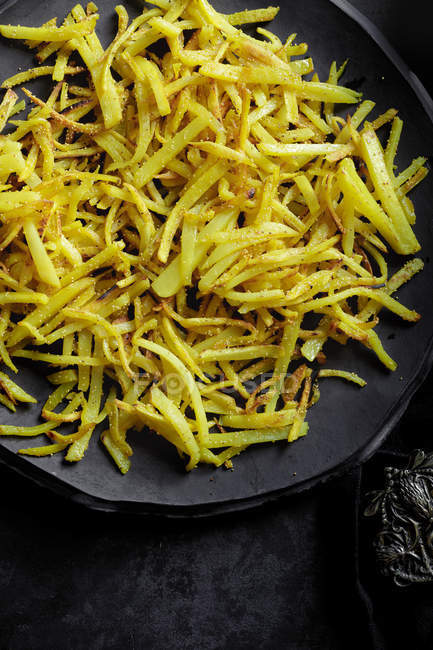 Patatine fritte su piatto su superficie nera — Foto stock