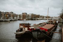 Amsterdam cityscape and traditional boats moored by canal embankment — Stock Photo