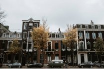 Paysage urbain pittoresque de la rue Amsterdam avec des voitures, des vélos de personnes par des façades de maisons typiques — Photo de stock