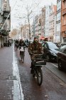 Personas montando bicicletas en la calle del casco antiguo, Amsterdam, Países Bajos - foto de stock