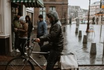Asian man riding bicycle on Amsterdam street in rainy weather, Netherlands — Stock Photo