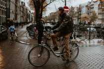 Человек на велосипеде у канала на одной из улиц Амстердама, Нидерланды — стоковое фото