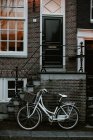 Arquitectura holandesa típica y bicicleta estacionada junto a la entrada de la casa, Amsterdam, Países Bajos - foto de stock