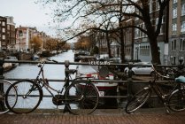 Знаменитый вид на город Амстердама с традиционной архитектурой, велосипедами, мостом через канал и пришвартованными лодками — стоковое фото