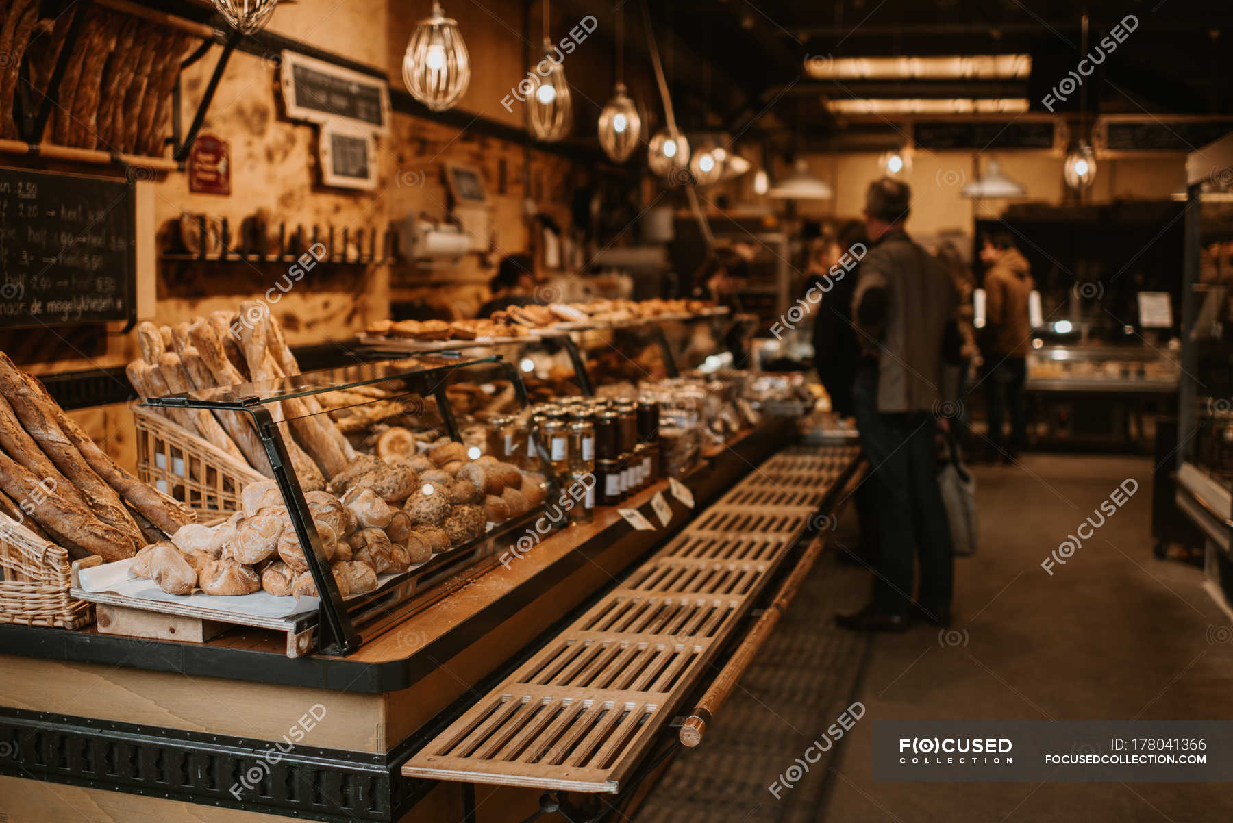 People at bakery store, counter with pastry view on foreground