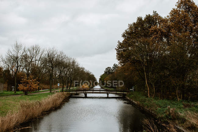 Park landscape with bridge over canal in moody daylight — Stock Photo