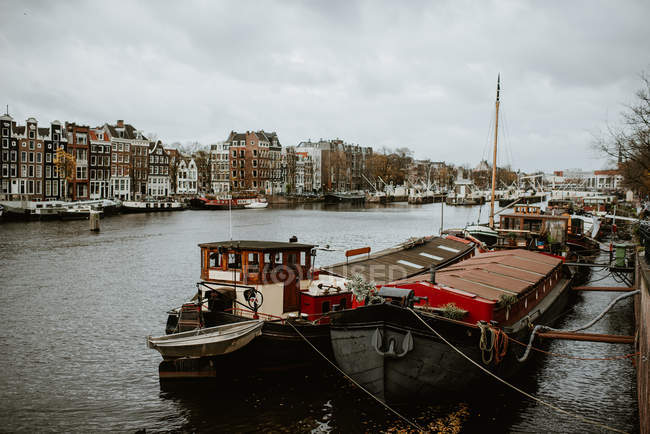 Amsterdam cityscape and traditional boats moored by canal embankment — Stock Photo