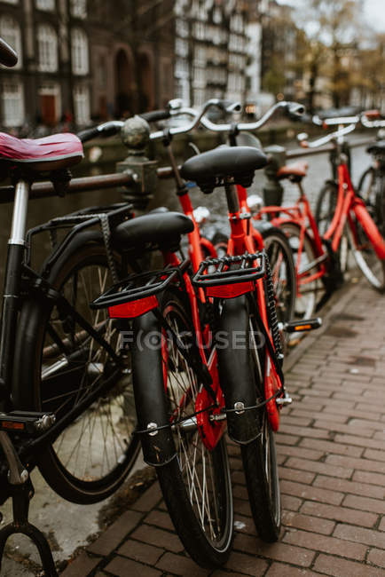 Vista trasera de las bicicletas rojas aparcadas junto al canal de Ámsterdam, Países Bajos - foto de stock