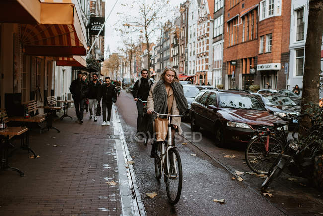 People riding bicycles on old town street, Amsterdam, Netherlands — Stock Photo