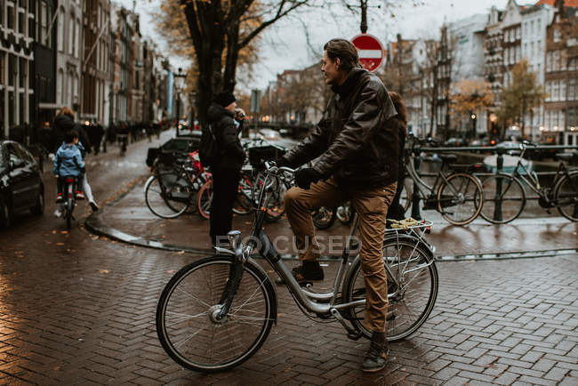 Homem de bicicleta pelo canal em uma das ruas da cidade de Amsterdã, Países Baixos — Fotografia de Stock