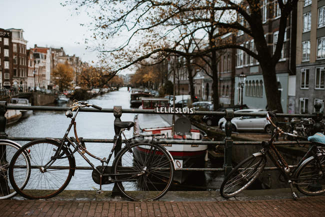 Знаменитый вид на город Амстердама с традиционной архитектурой, велосипедами, мостом через канал и пришвартованными лодками — стоковое фото