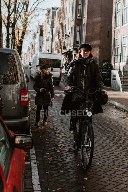 Donna in bicicletta sulla tipica strada di Amsterdam, guardando la fotocamera — Foto stock