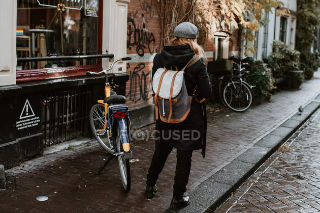Rear view of young woman on Amsterdam street with bicycles in downtown — Stock Photo