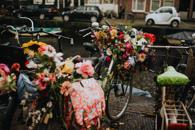 Vélos avec bouquets de fleurs sur la rue Amsterdam au bord du canal — Photo de stock