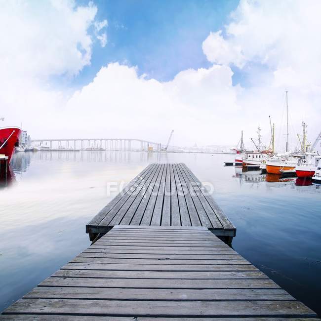 Doca de passarela de madeira no porto com barcos e bela paisagem nublada — Fotografia de Stock