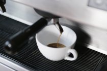 Close up view of espresso pouring from coffee machine in cup — Stock Photo