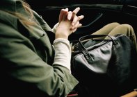 Mujer de la cosecha sentado en el coche con bolso - foto de stock