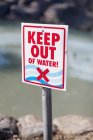 Keep Out of Water sign posted on rocky beach — Stock Photo