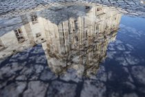 Reflection of Cathedral facade in paddle on paved street — Stock Photo