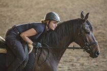 Вид сбоку на женщину верхом на лошади на ранчо — стоковое фото