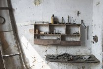 Interior del taller abandonado con varias herramientas en el banco de trabajo de los estantes - foto de stock