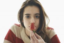 Chica sosteniendo fresa en frente de la boca sobre fondo blanco - foto de stock