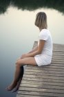 Vista laterale della donna seduta sul molo — Foto stock
