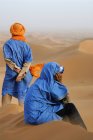Moroccan men dressed in traditional clothing sitting at dunes — Stock Photo