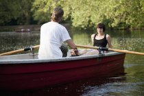 Young couple sitting in rowboat on lake in nature — Stock Photo