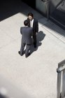Dos hombres de negocios hablando al aire libre junto al edificio de oficinas - foto de stock
