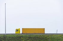 Yellow semi-truck on bridge against clear sky — Stock Photo